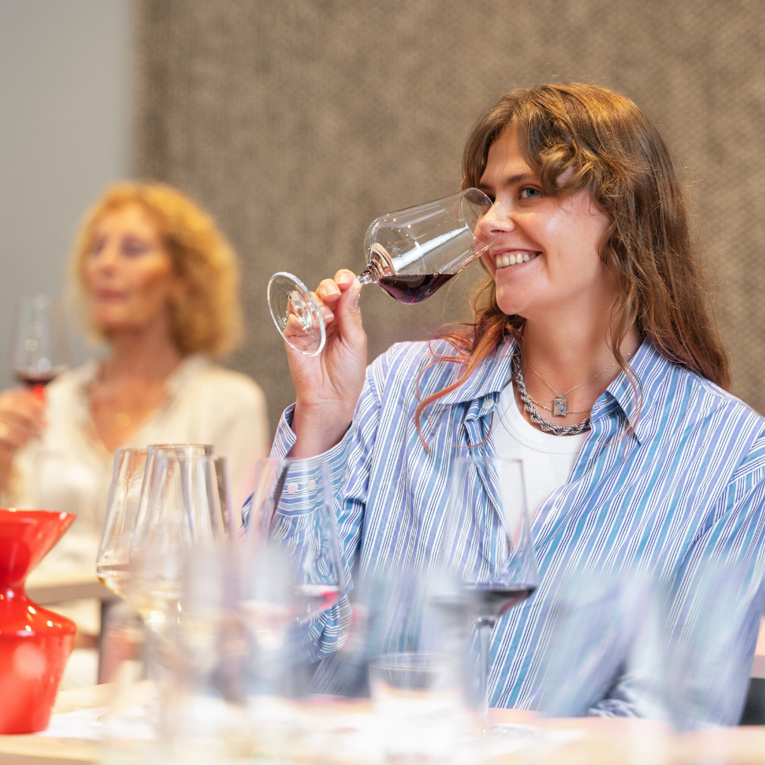 Bild på student som doftar på vin under en föreläsning på sommelierutbildningen.