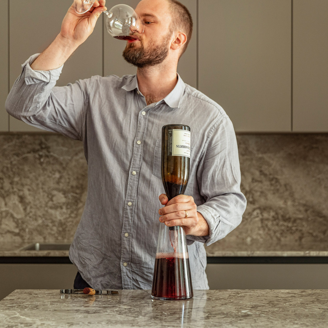 Hans provar vin samtidigt som han dekanterar en flaska Bourgogne.